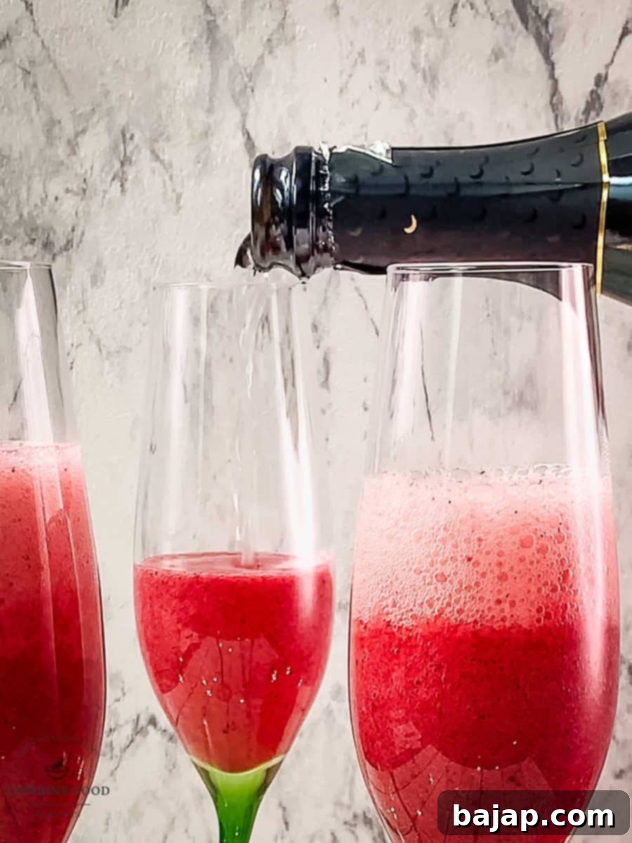 Slowly pour sparkling wine into the glasses filled with berry smoothie, creating a beautiful mimosa.