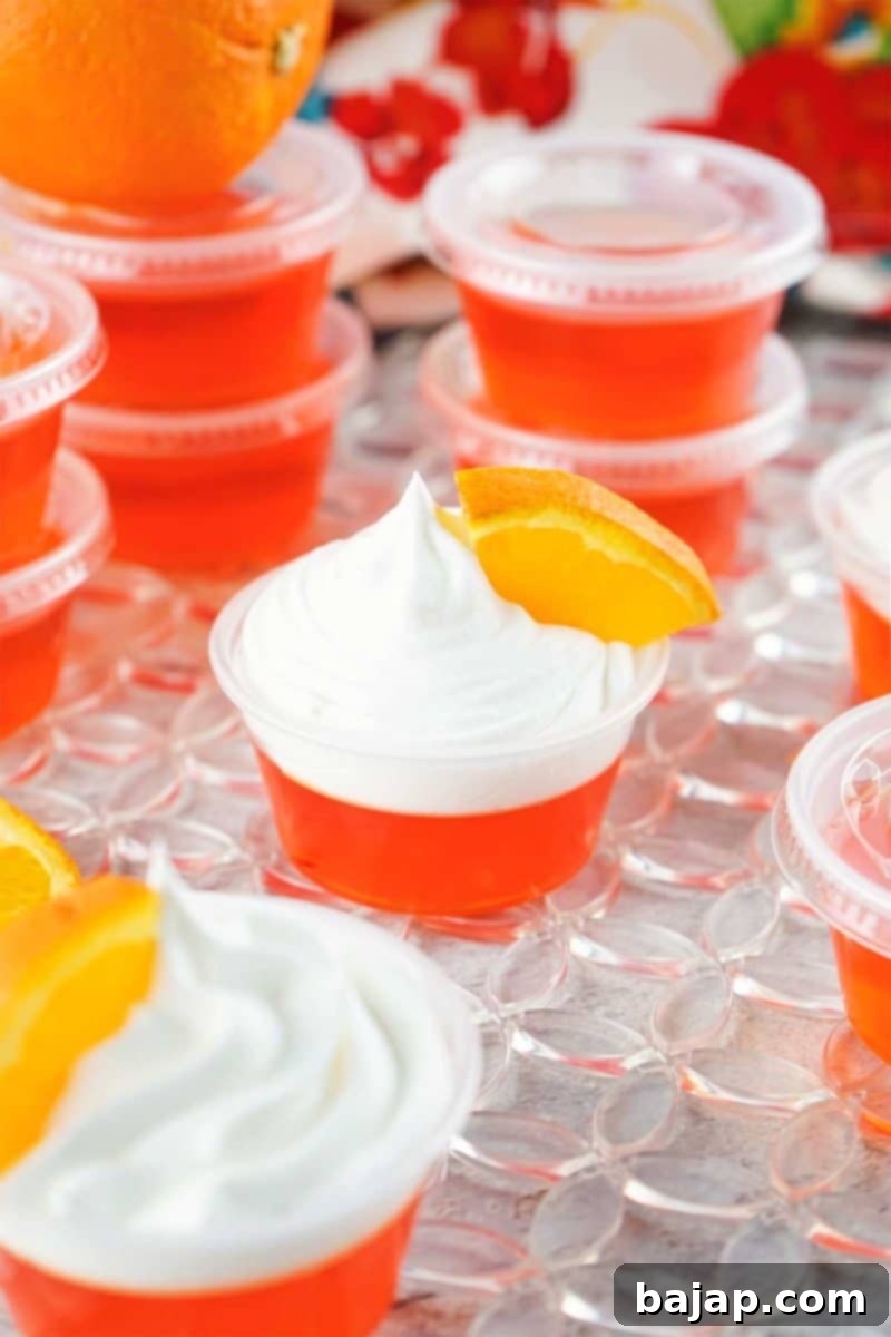 Fun Mimosa Jello Shots, capturing the classic mimosa flavor with orange gelatin and champagne, garnished with whipped cream and orange slices.
