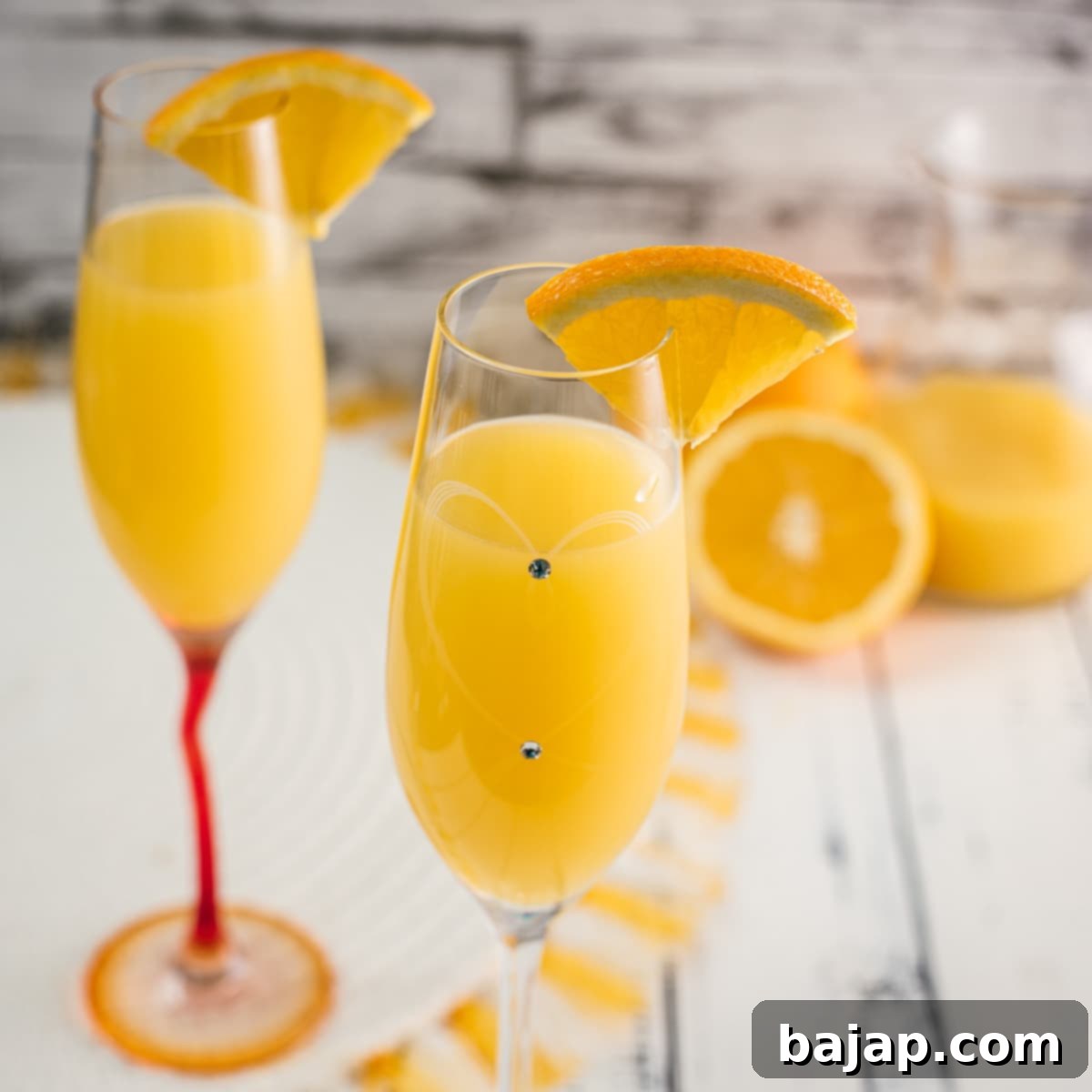 Gorgeous classic mimosa, garnished with an orange slice in an elegant flute glass, perfect for any brunch.