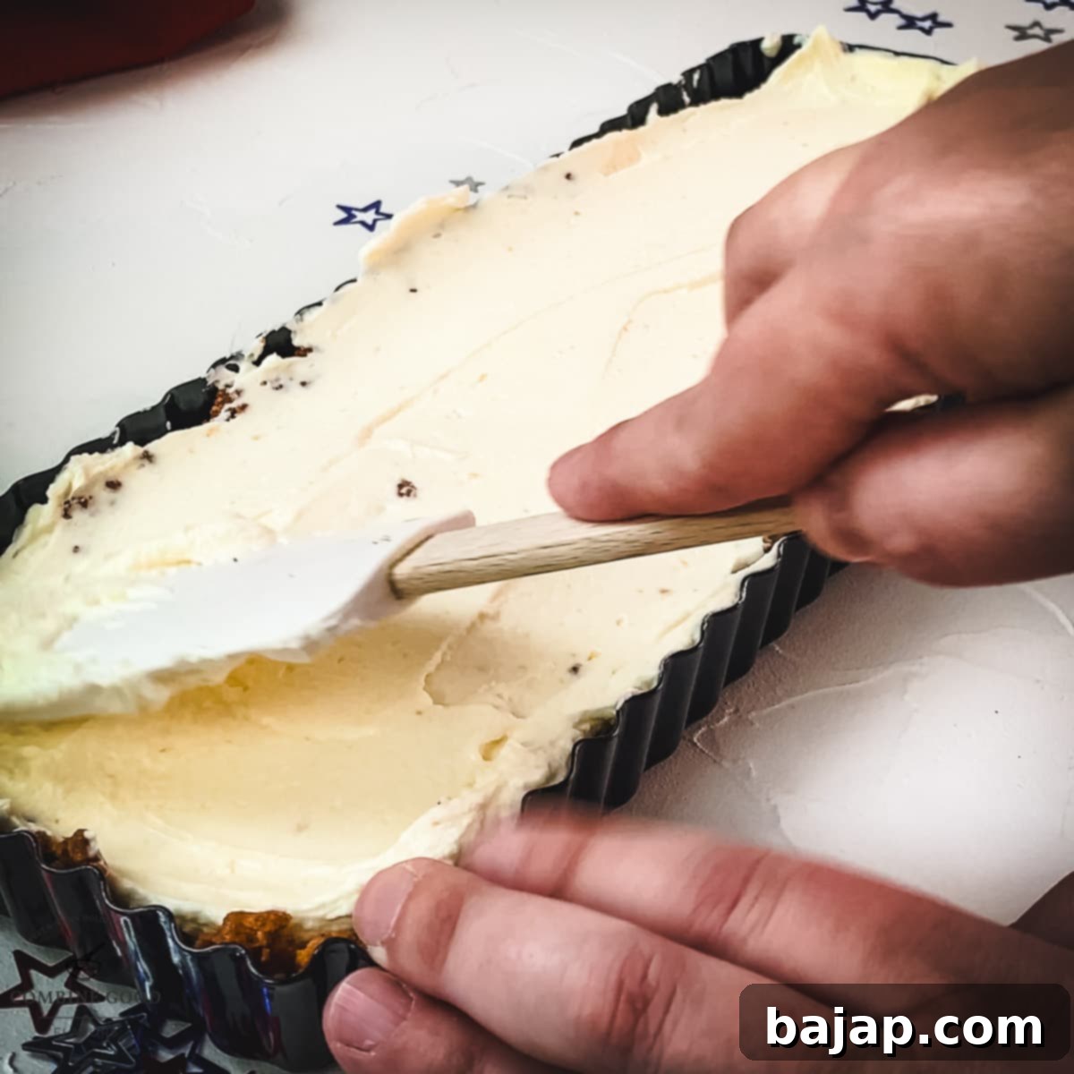 Spreading the smooth and creamy cream cheese filling over the chilled Lotus Biscoff crust.