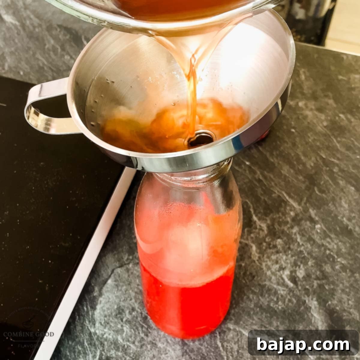 Using a funnel to fill hot watermelon syrup into a clean preserving jar.
