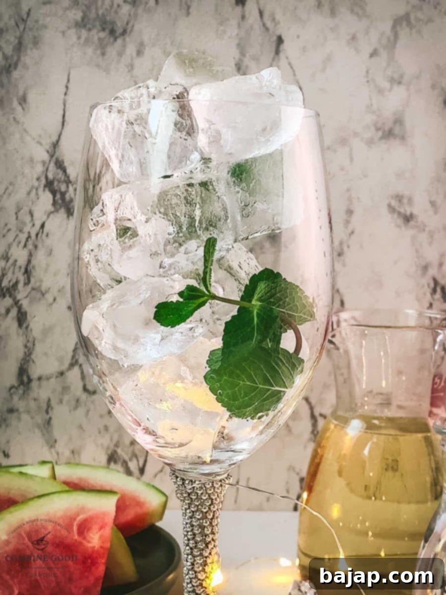Adding cubed ice and mint leaves to the wine glass.