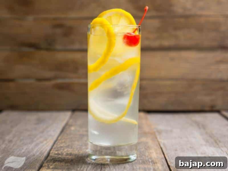 Classic Tom Collins cocktail with lemon and a cherry garnish.