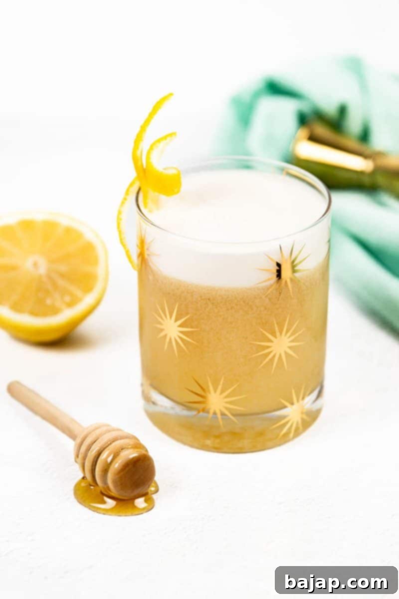 Honey Lemon Whiskey Sour, also known as a Gold Rush Cocktail, with ice and lemon.