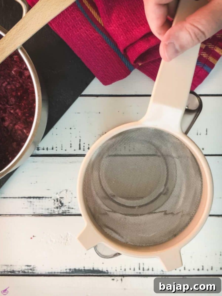 Placing a fine-meshed sieve on top of a tall container, preparing for straining.