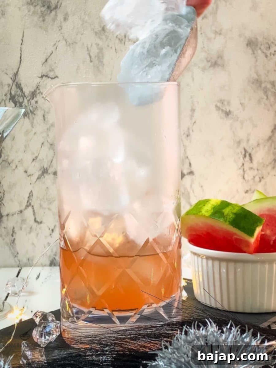Adding cubed ice to the stirring glass, ready for chilling and mixing.