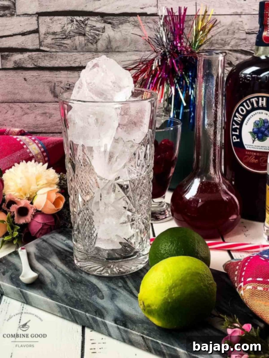 A highball glass is generously filled with sparkling cubed ice, resting on a marbled plate, ready for the next ingredients.