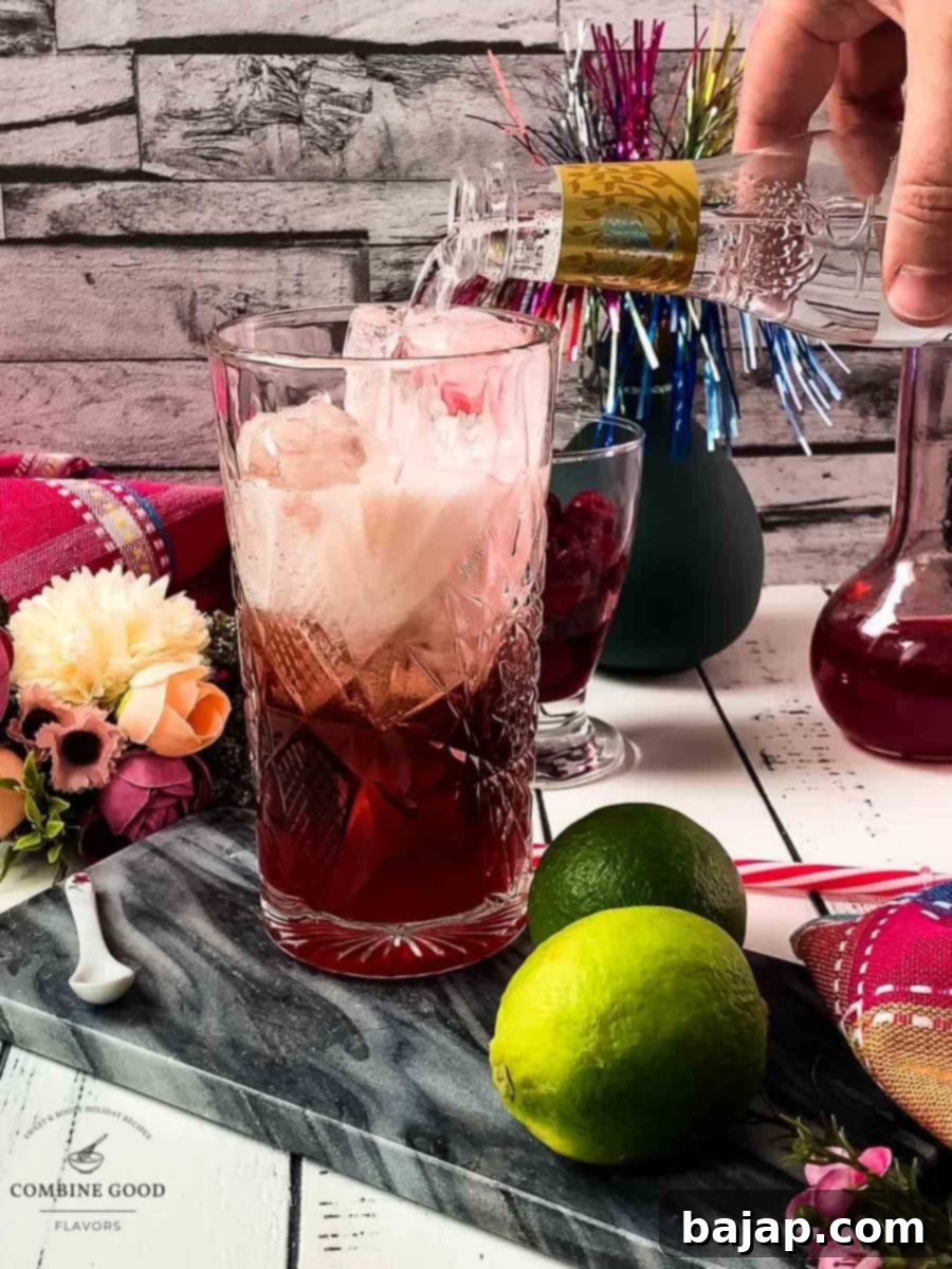 Topping off the drink with effervescent tonic water, creating a beautiful layered effect.
