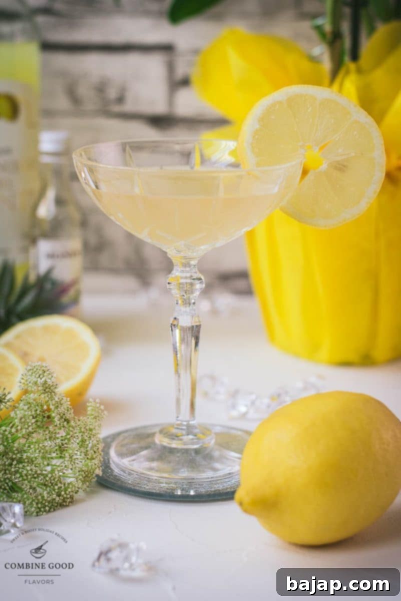 An elegantly presented Limoncello Martini with elderflower syrup, garnished with a lemon slice and resting on a mirrored coaster, perfect for a chic evening.