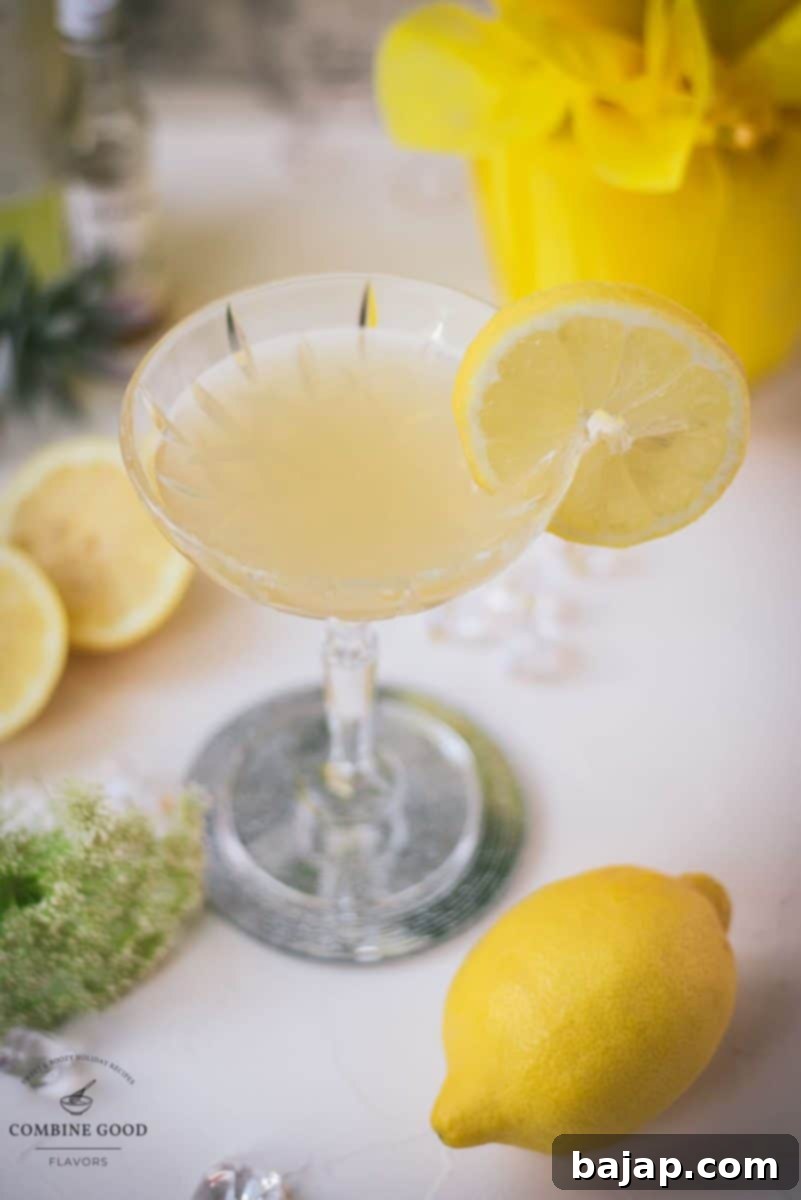 A vibrant Limoncello Martini with elderflower syrup, garnished with a crisp lemon slice, elegantly poised on a reflective coaster, ready to be enjoyed.