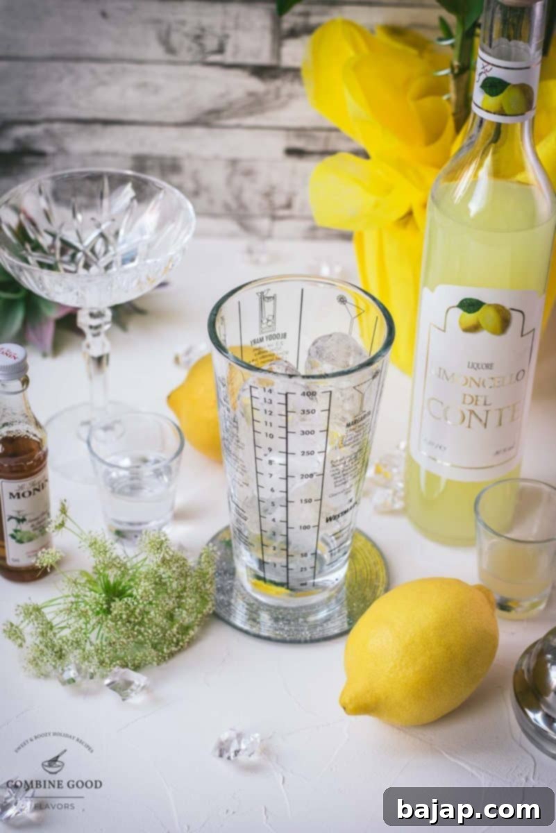 All the essential ingredients neatly arranged for a Limoncello Martini with elderflower syrup: a bottle of high-quality vodka, a bottle of authentic Limoncello, Monin Elderflower Syrup, freshly squeezed lemon juice in a small pitcher, and sparkling cubed ice, promising a delicious mix.
