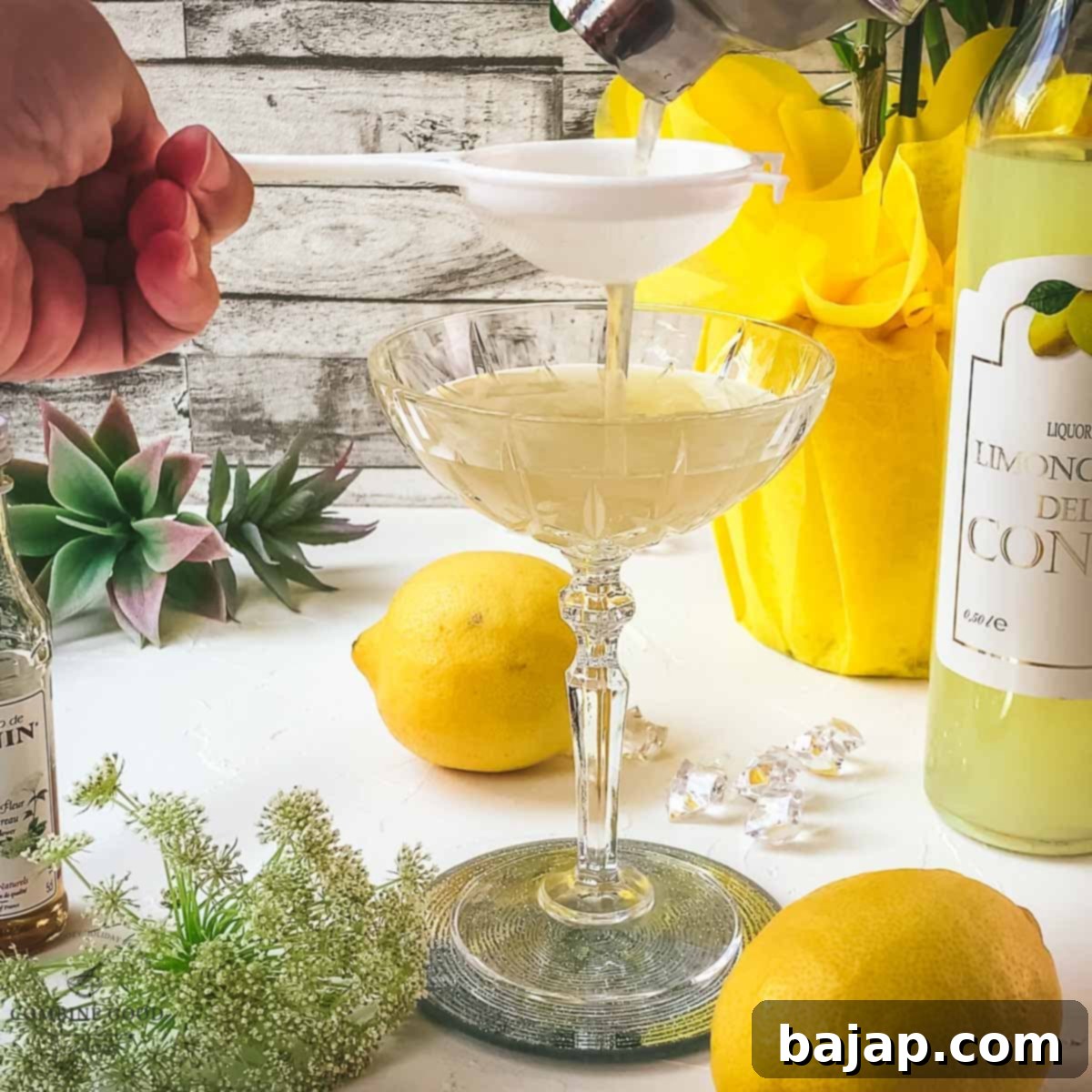 A Limoncello Elderflower Martini being fine-strained from a shaker into an elegant cocktail glass, ensuring a smooth, crystal-clear pour.