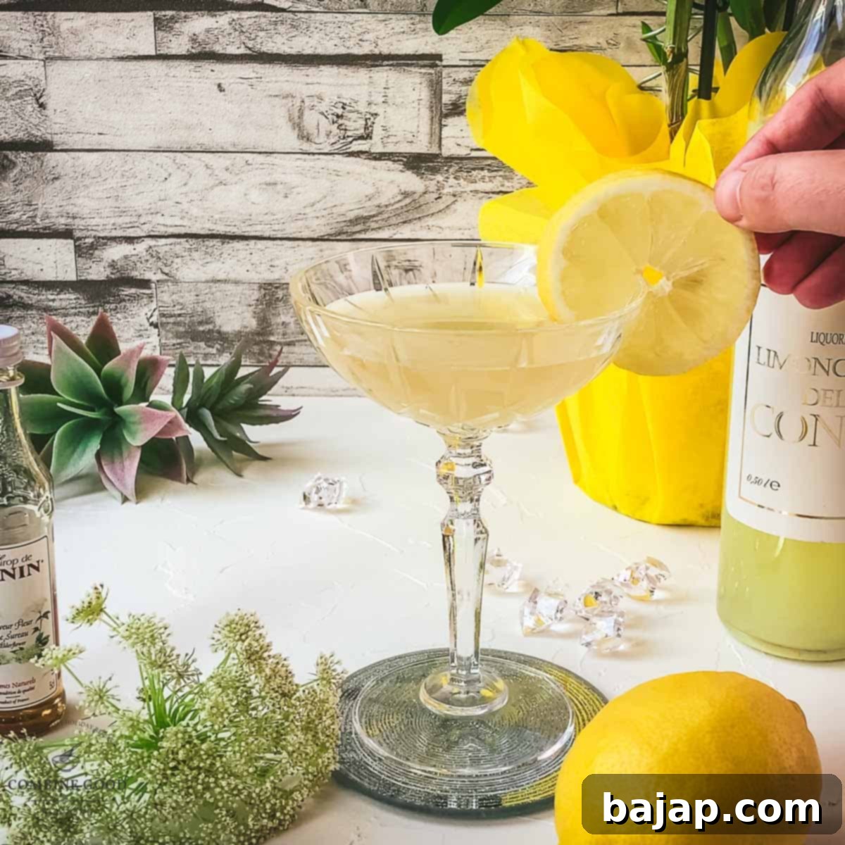 A hand gently placing a thin, vibrant lemon slice on the rim of a cocktail glass, serving as the final garnish for the Limoncello Martini.