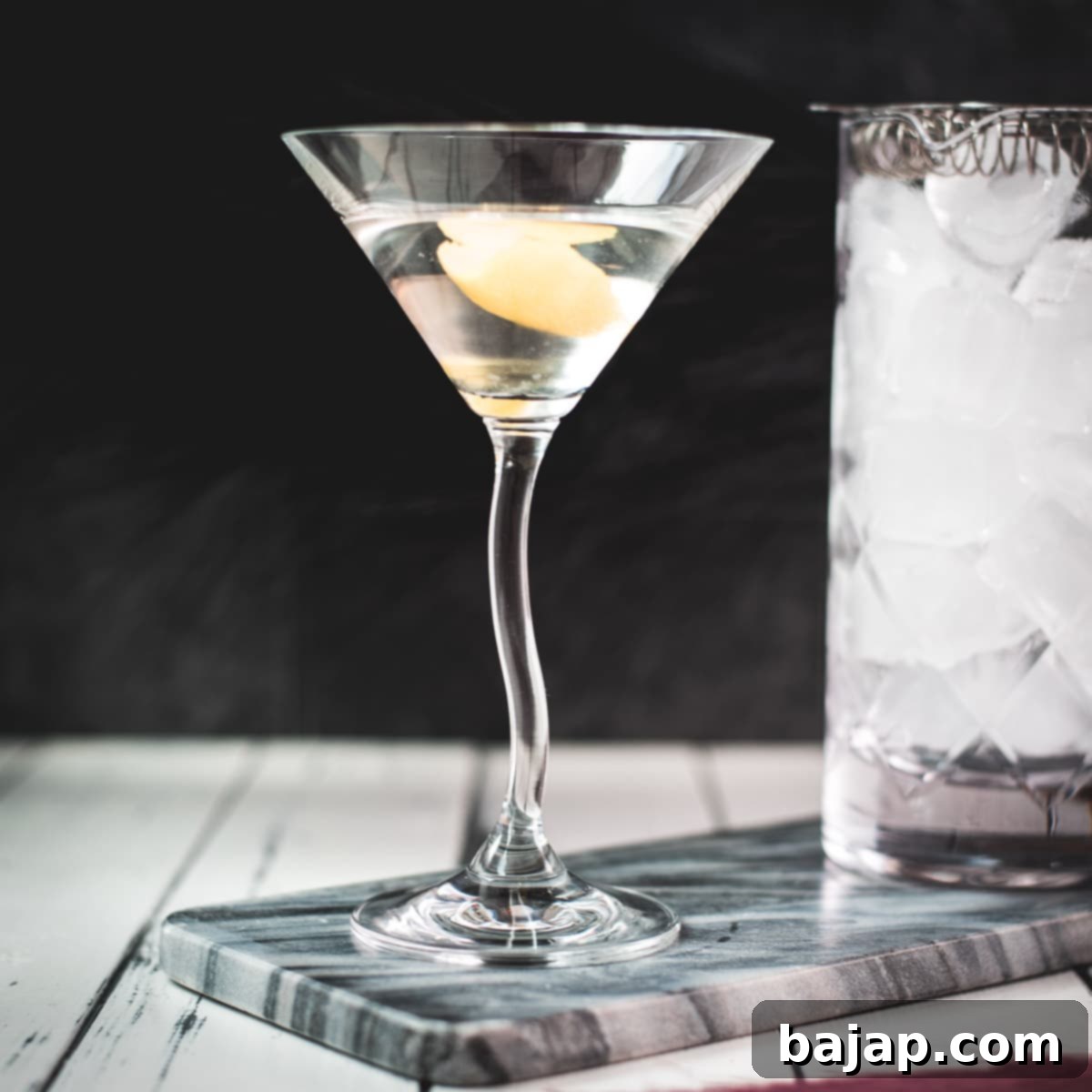Elegant cocktail glass, placed on marbled plate, and garnished with a lemon zest.