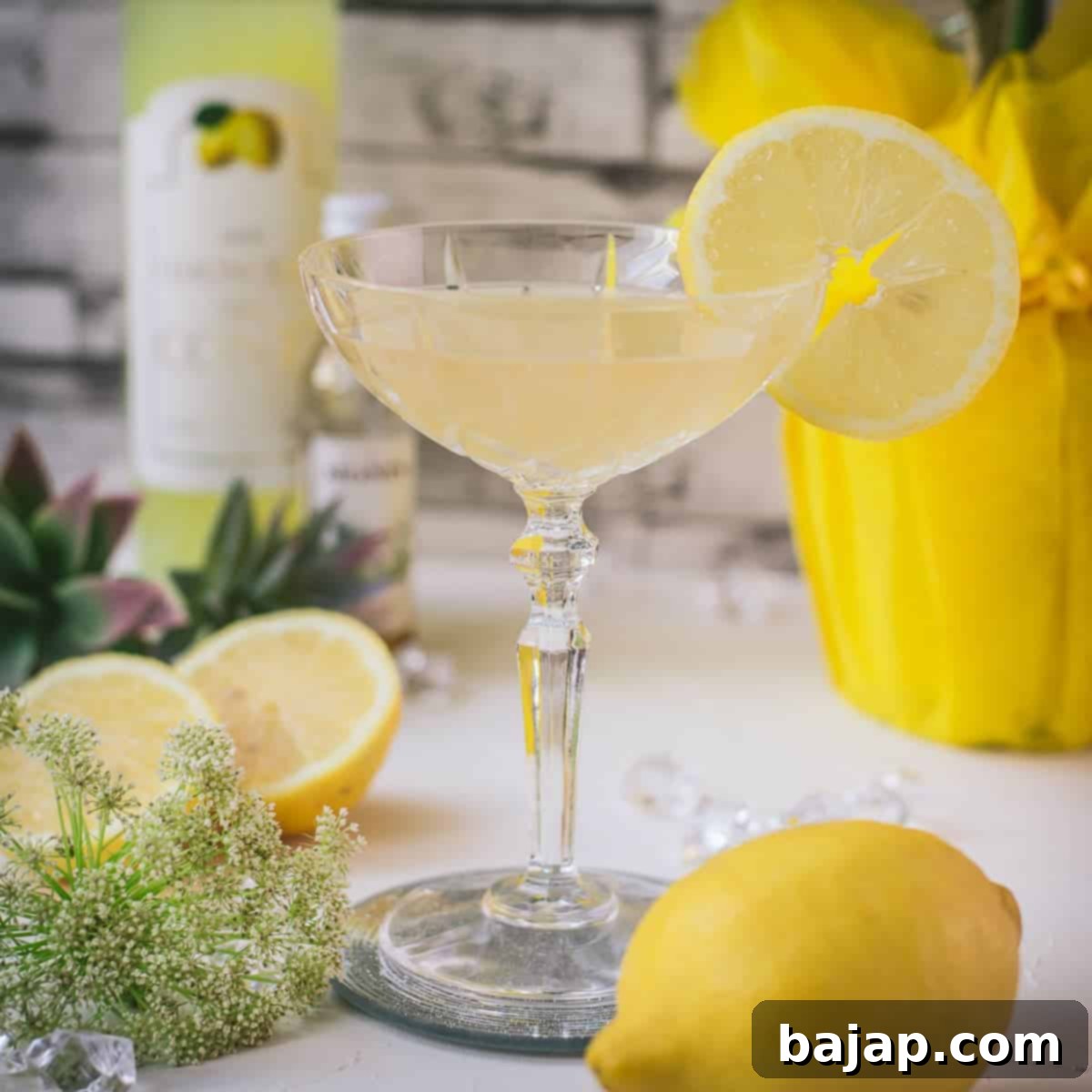 Gorgeous Limoncello Martini cocktail with elderflower syrup. Garnished with a lemon slice and placed on a mirrored coaster.