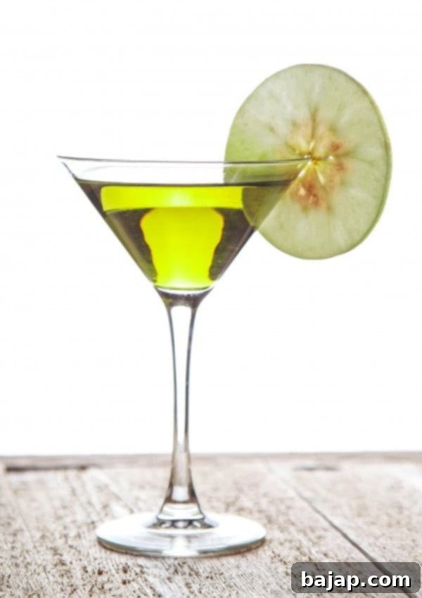 Appletini cocktail garnished with an apple slice