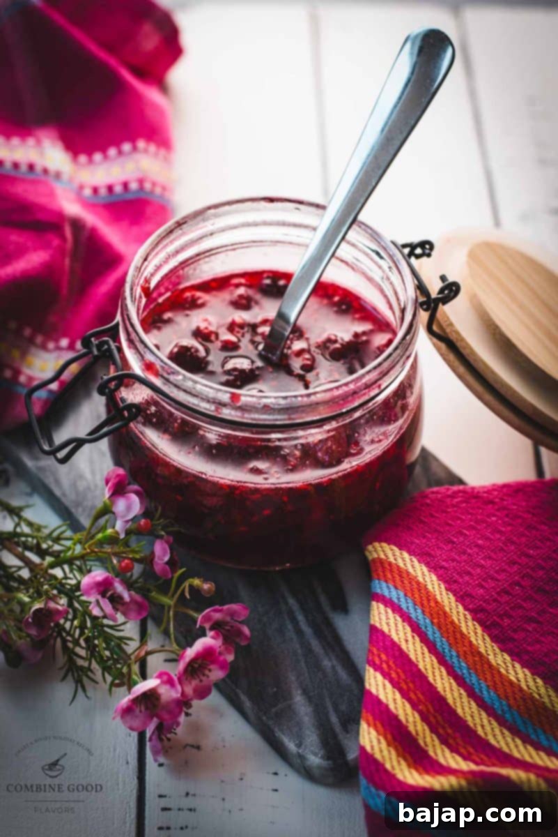 Preserving jar, filled with delicious uncooked raspberry syrup placed on a marbled plate.
