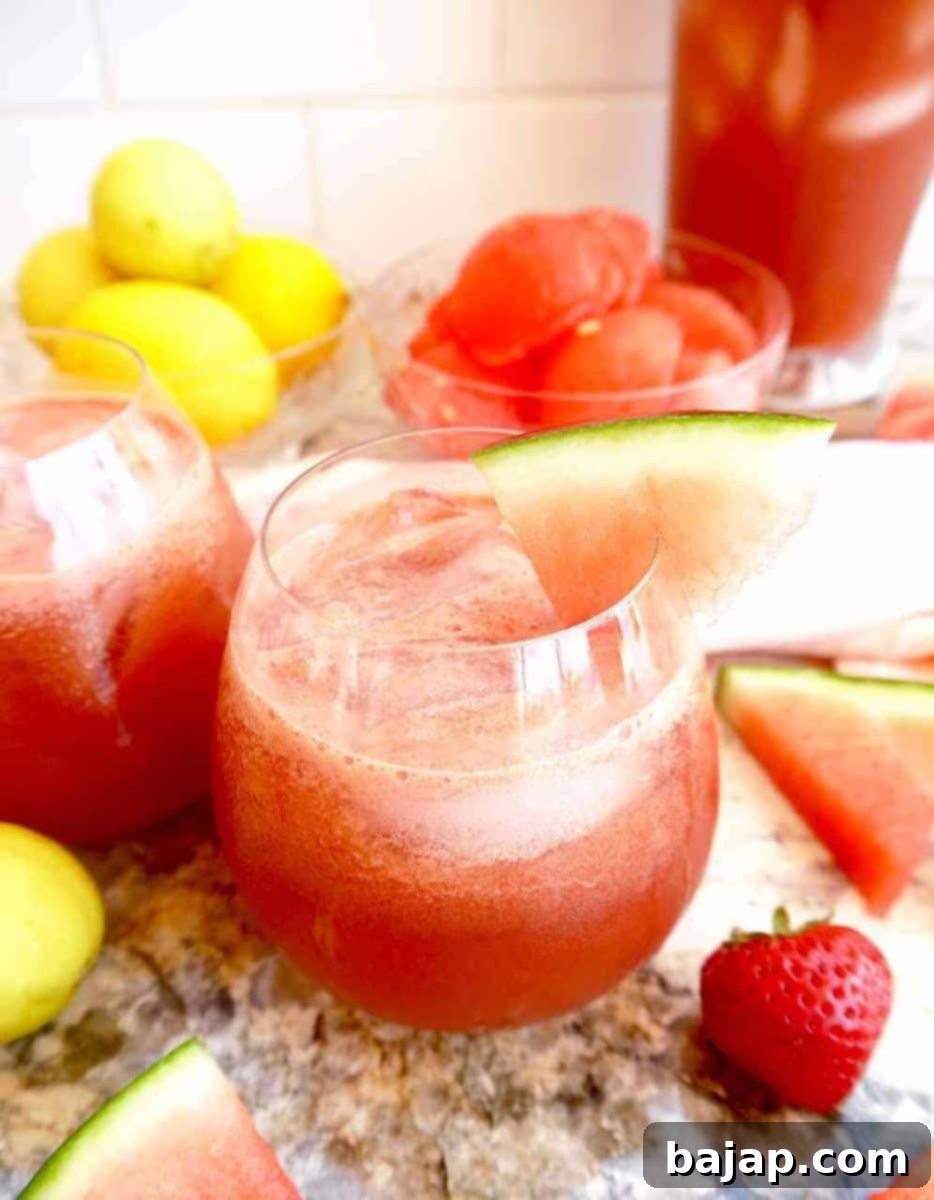 A glass of vibrant strawberry watermelon juice with cucumber, garnished with fresh mint.