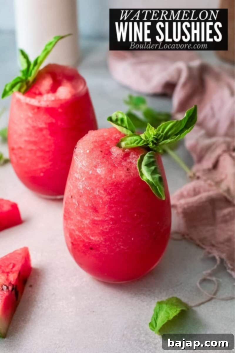 A vibrant red watermelon wine slushie in a stemmed glass, garnished with fresh mint.