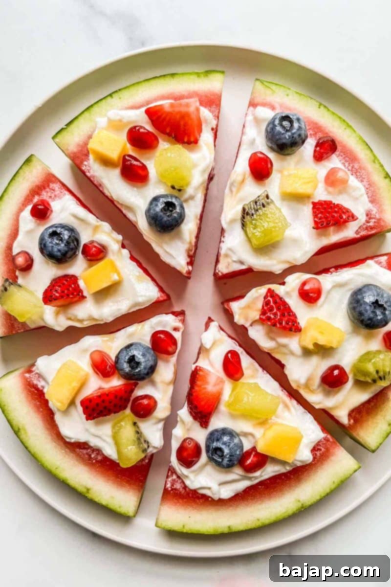 A creative watermelon pizza topped with yogurt, fresh berries, and mint, sliced and ready to eat.