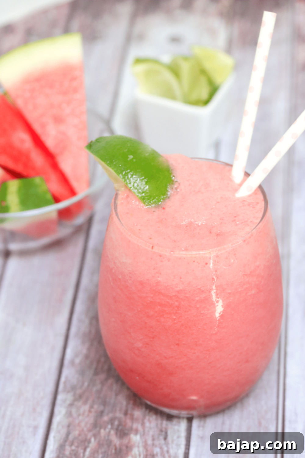 A tall glass of fizzy watermelon slushie garnished with a fresh slice of watermelon, perfect for cooling down.