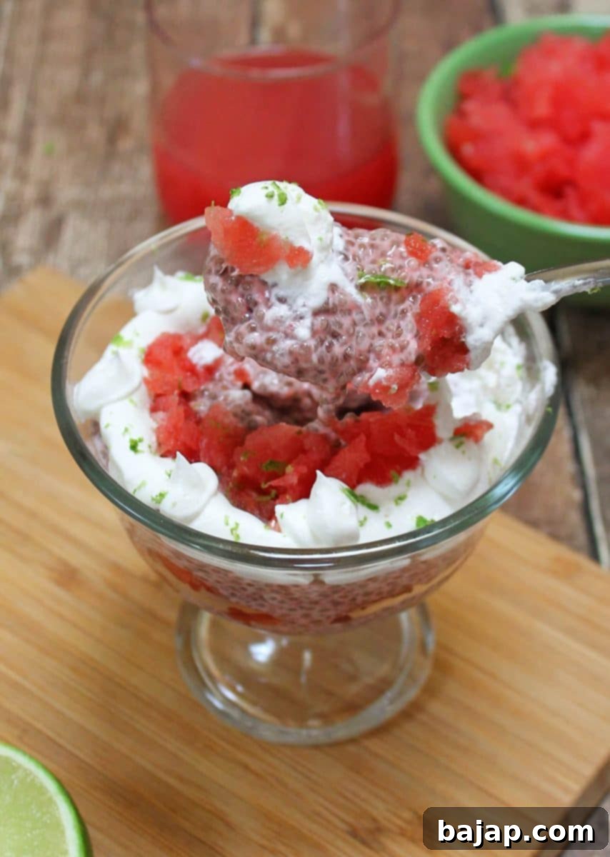 A vibrant Watermelon Chia Parfait layered in a glass with whipped topping and fresh mint leaves.