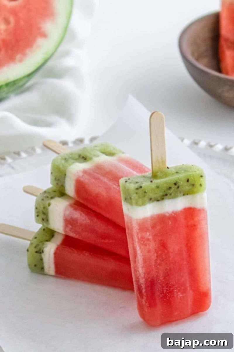 Easy homemade watermelon popsicles, shaped like watermelon slices, on a light background.