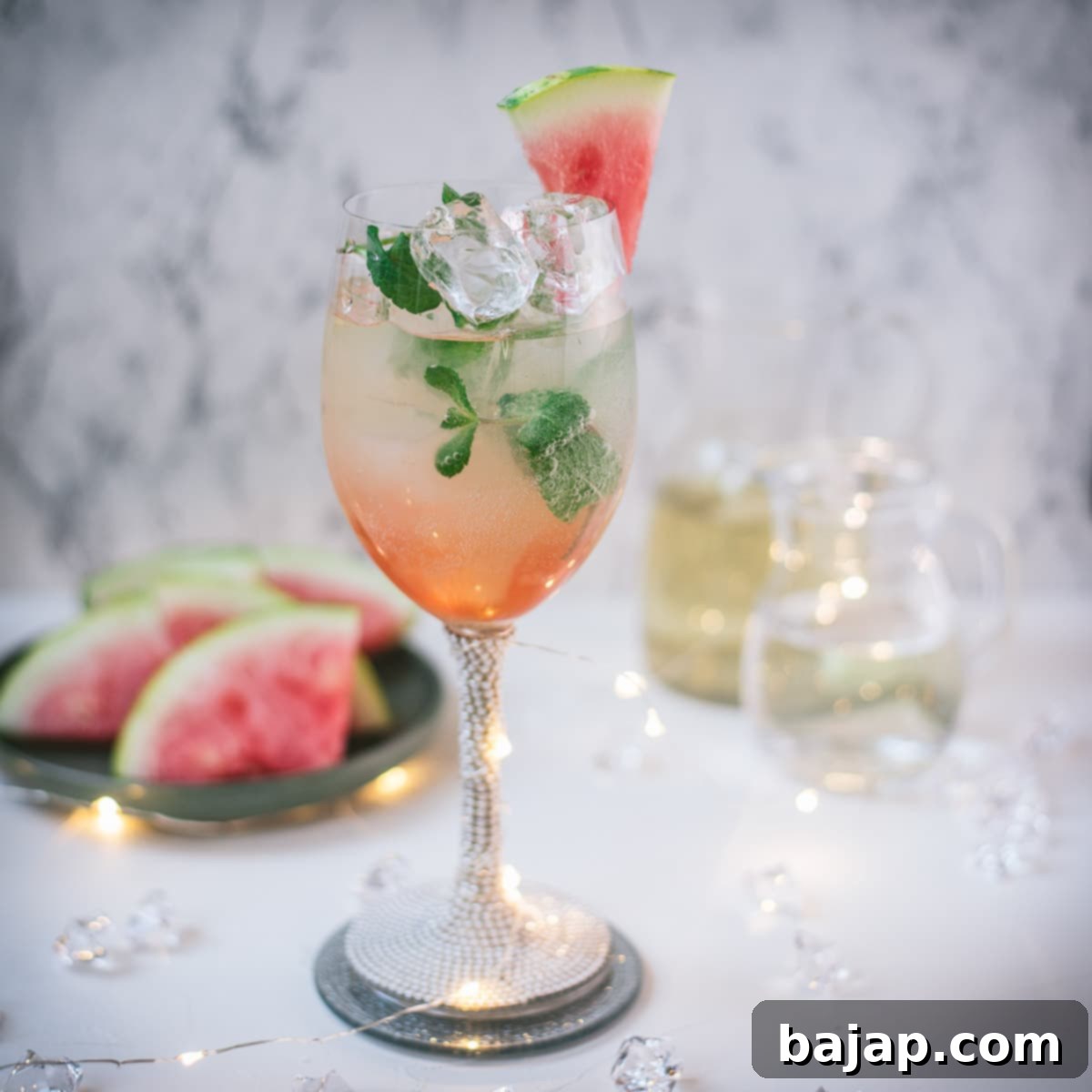 A gorgeous wine glass filled with a vibrant pink watermelon spritzer, garnished with fresh mint.