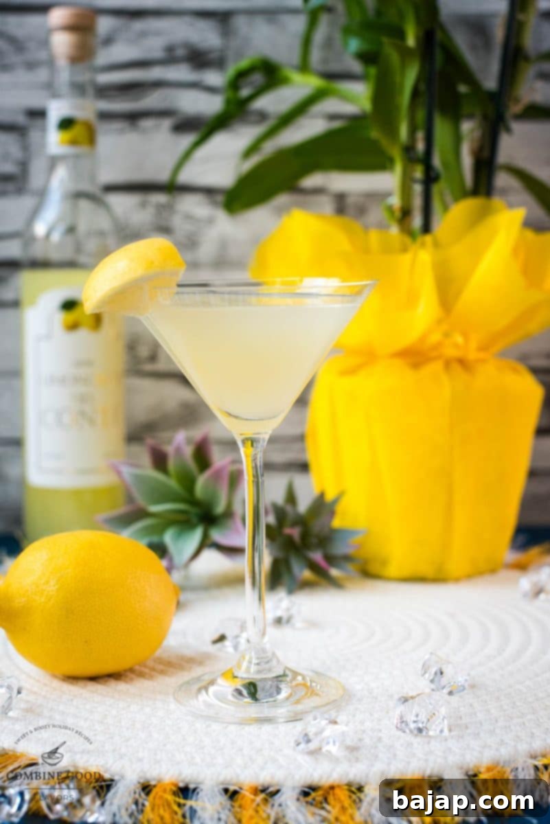 Gorgeous cocktail glass filled with a vibrant limoncello martini, garnished with a lemon wedge.