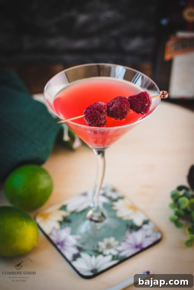 Delicious raspberry margarita served in a chic cocktail glass and garnished with fresh raspberries on a cocktail pike, set against a bright, inviting backdrop.