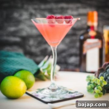 Delicious raspberry margarita served in cocktail glass and garnished with fresh raspberries on a cocktail pike.