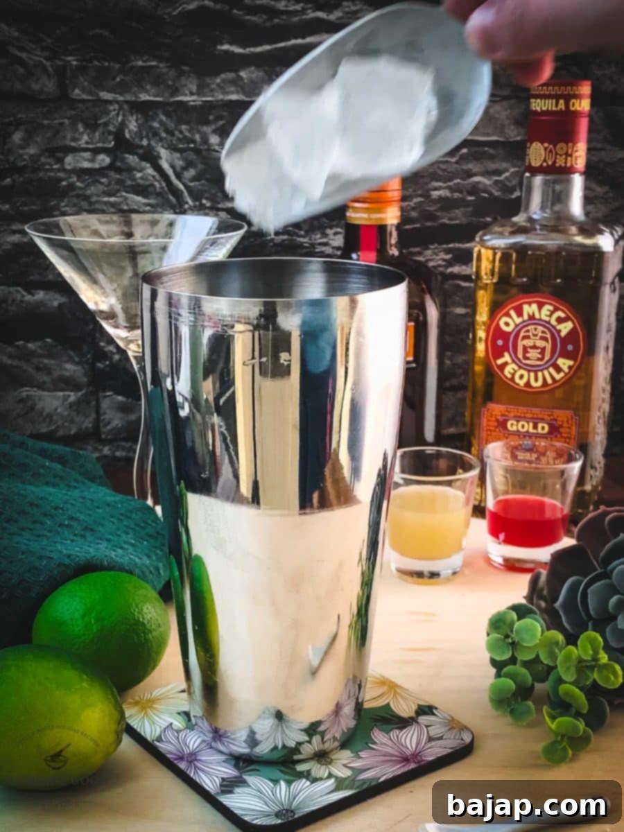 Adding fresh cubed ice to a professional cocktail shaker.