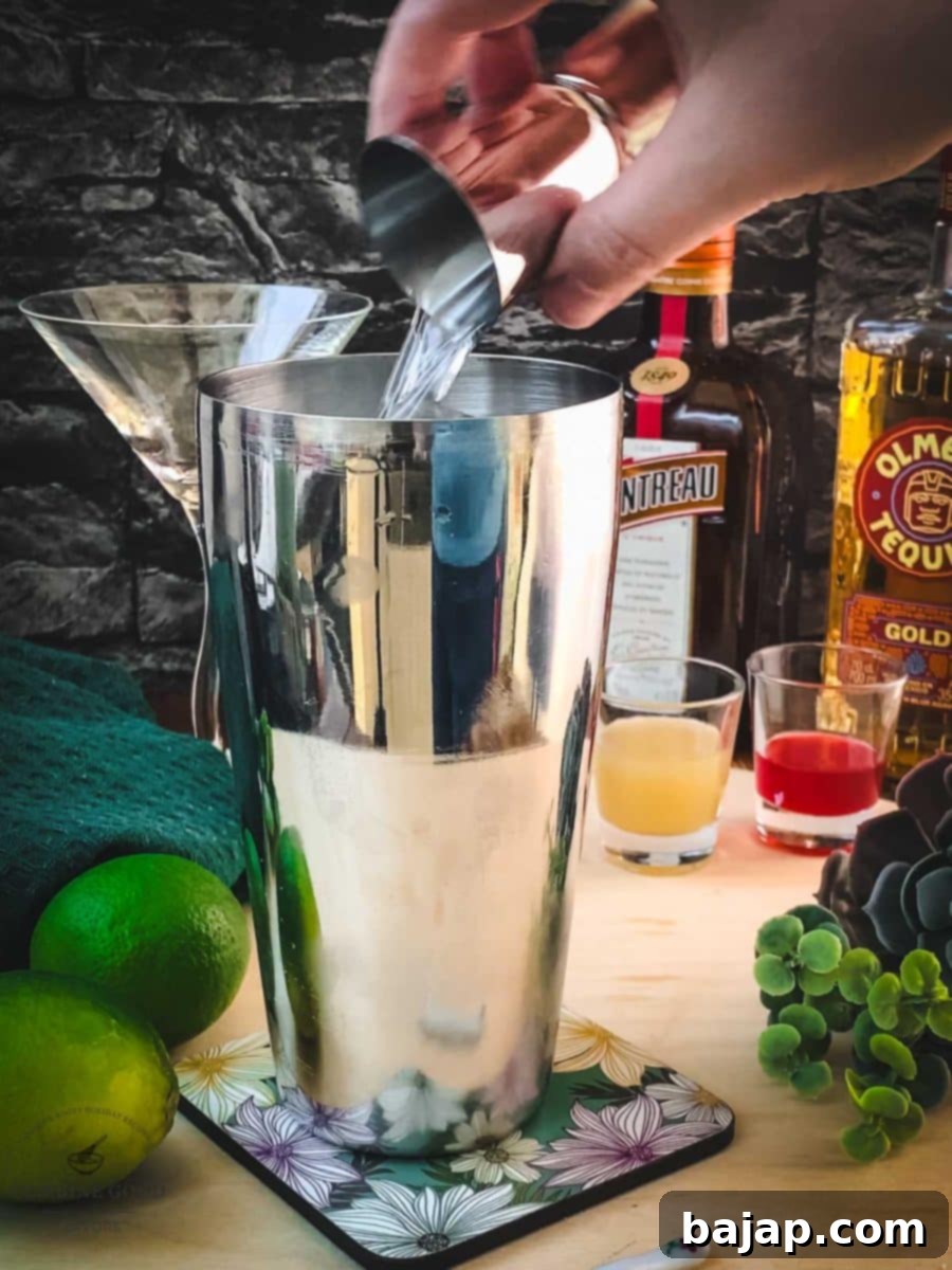 Adding Cointreau, a premium orange liqueur, to the cocktail shaker.