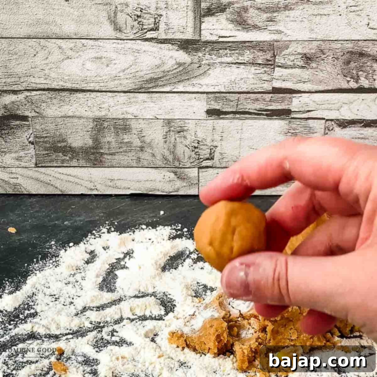 Dough ball between thumb and forefinger show the size of the peanut butter cookie.