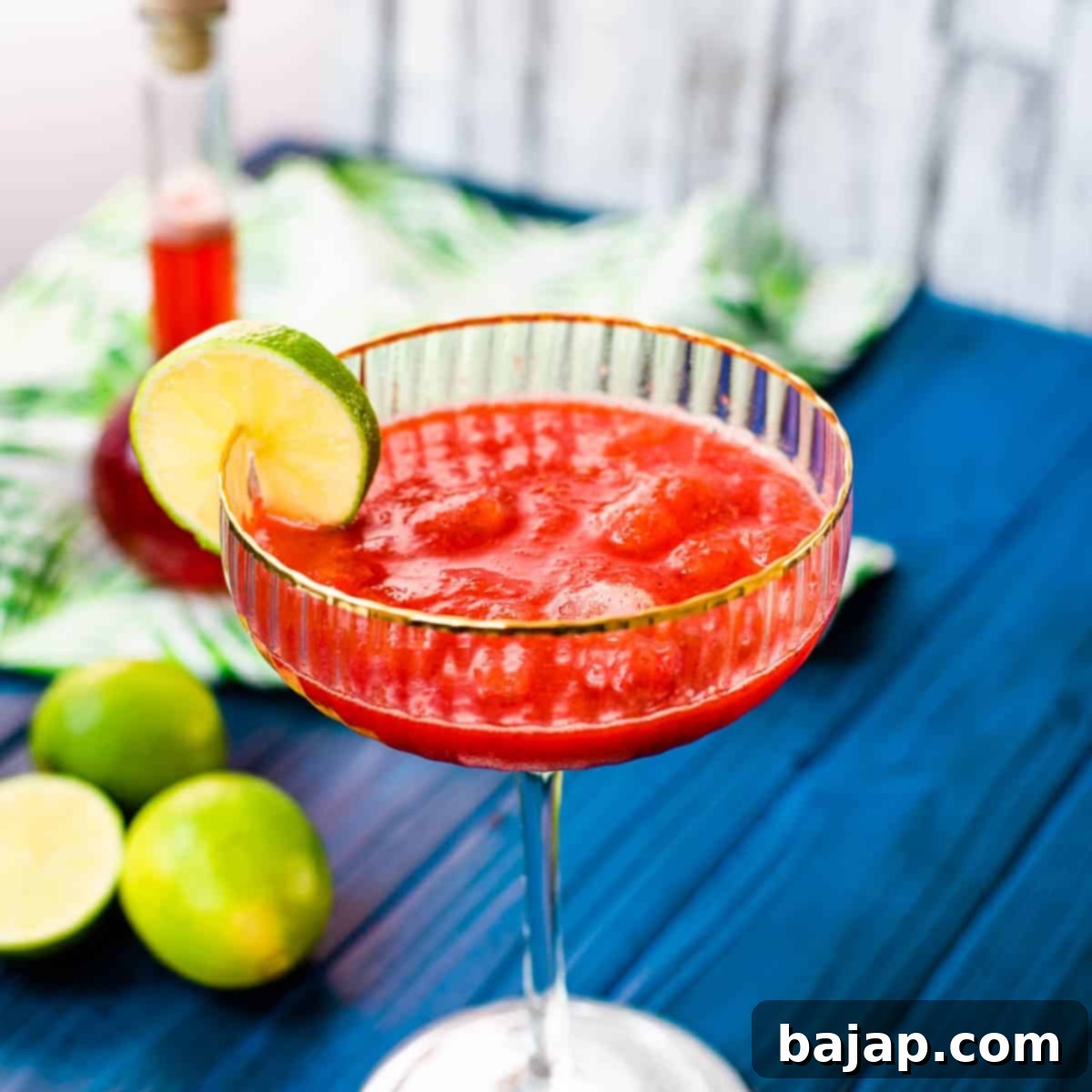 Gorgeous cocktail glass, with golden rim, filled with frozen strawberry daiquiri.