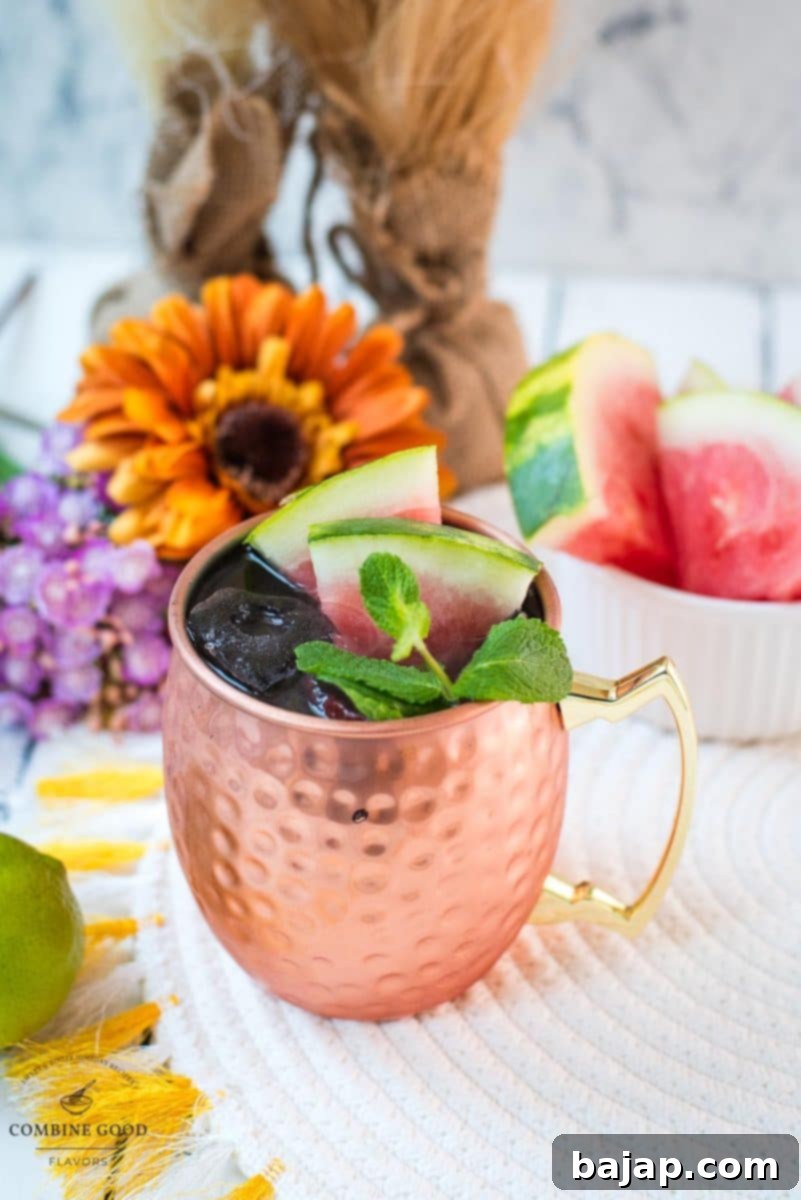 A beautifully chilled copper mug filled with a vibrant Watermelon Moscow Mule, garnished with fresh watermelon slices and aromatic mint leaves, set against a summer backdrop.