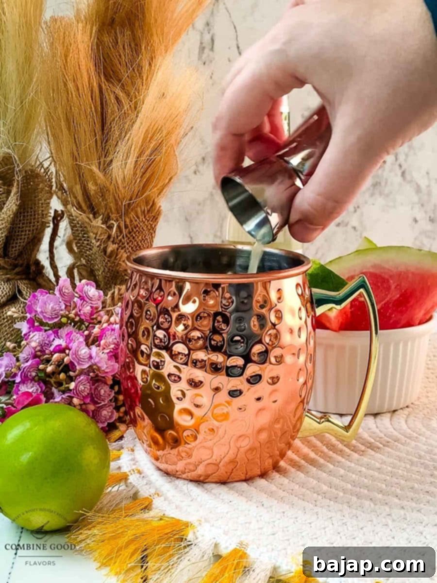 Squeezing fresh lime juice directly into the copper mug with vanilla vodka and watermelon syrup, adding a tangy zest to the cocktail.