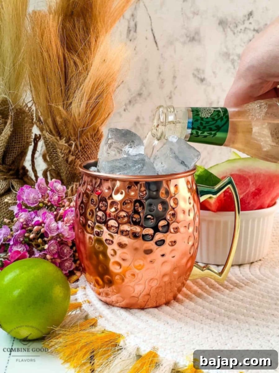 Topping off the Watermelon Moscow Mule with a fizzy pour of ginger beer, creating a refreshing and spicy finish.