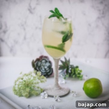 Refreshing White Wine Hugo Spritz Recipe 12 Stunning wine glass filled with Hugo spritz cocktail, placed on a white plate and garnished with mint leaves and lime slices.