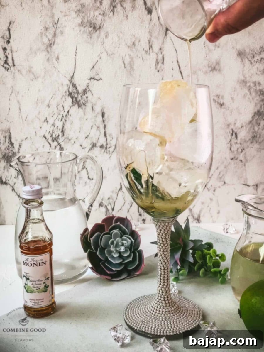 Refreshing White Wine Hugo Spritz Recipe 5 Adding freshly squeezed lime juice and sweet elderflower syrup into a wine glass already filled with cubed ice, preparing the base for the Hugo Spritz.