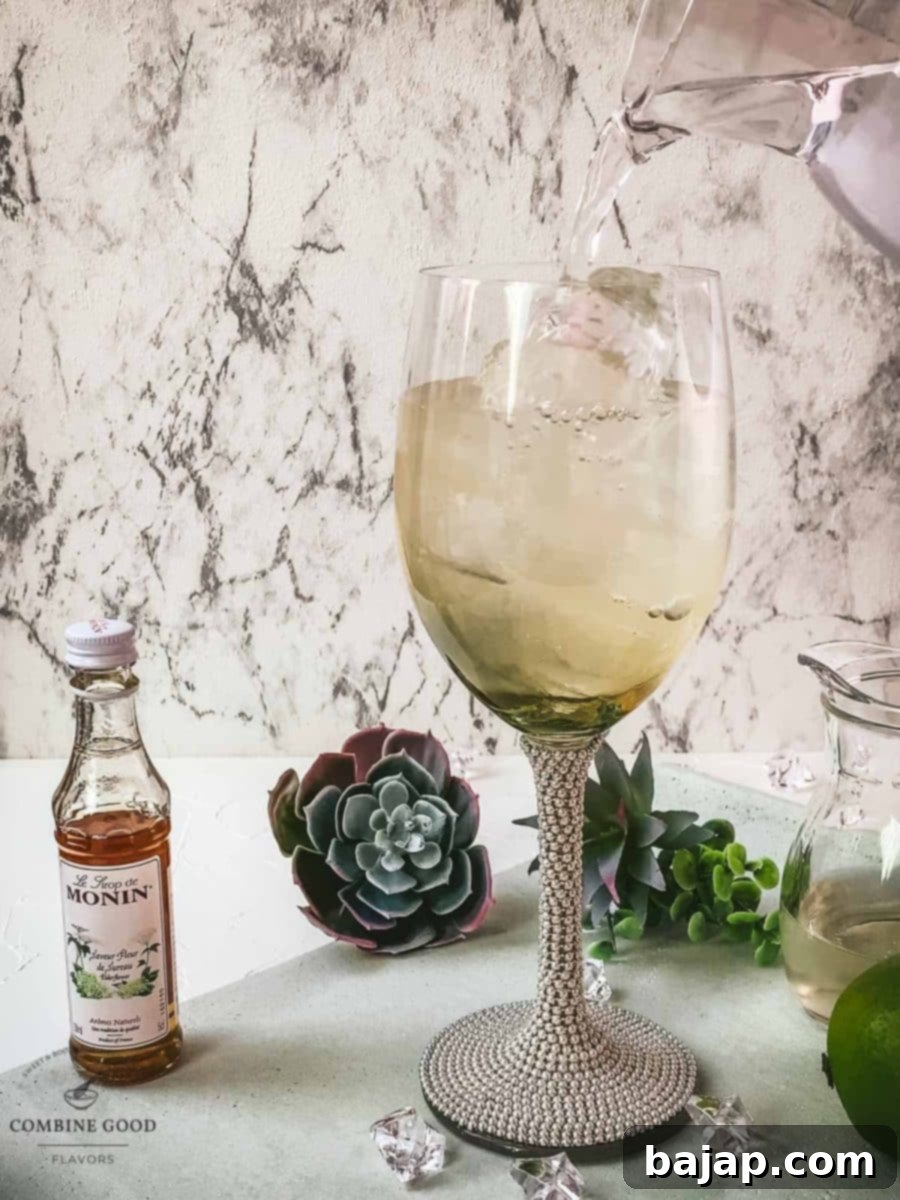 Refreshing White Wine Hugo Spritz Recipe 7 Topping off the Hugo Spritz in the wine glass with sparkling mineral water, adding the final effervescent touch to the refreshing cocktail.