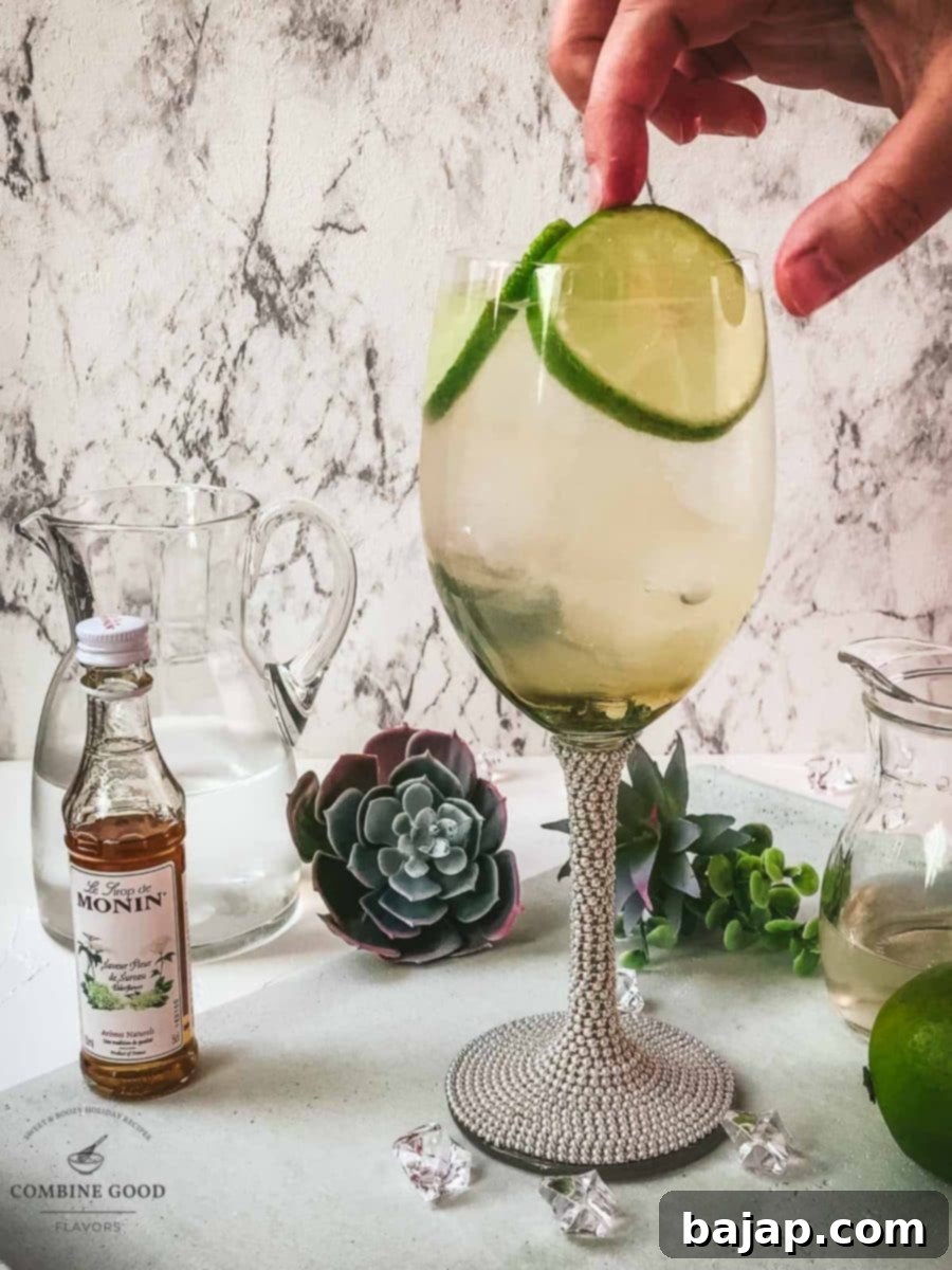 Refreshing White Wine Hugo Spritz Recipe 8 Garnishing the prepared Hugo Spritz cocktail with fresh lime slices, adding both visual appeal and an extra hint of citrus flavor.
