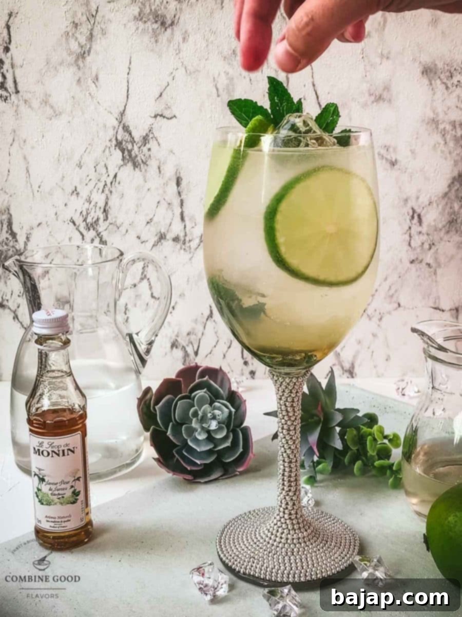 Refreshing White Wine Hugo Spritz Recipe 9 Final step of garnishing the Hugo Spritz cocktail with a sprig of fresh mint leaves, enhancing its aroma and visual appeal before serving.