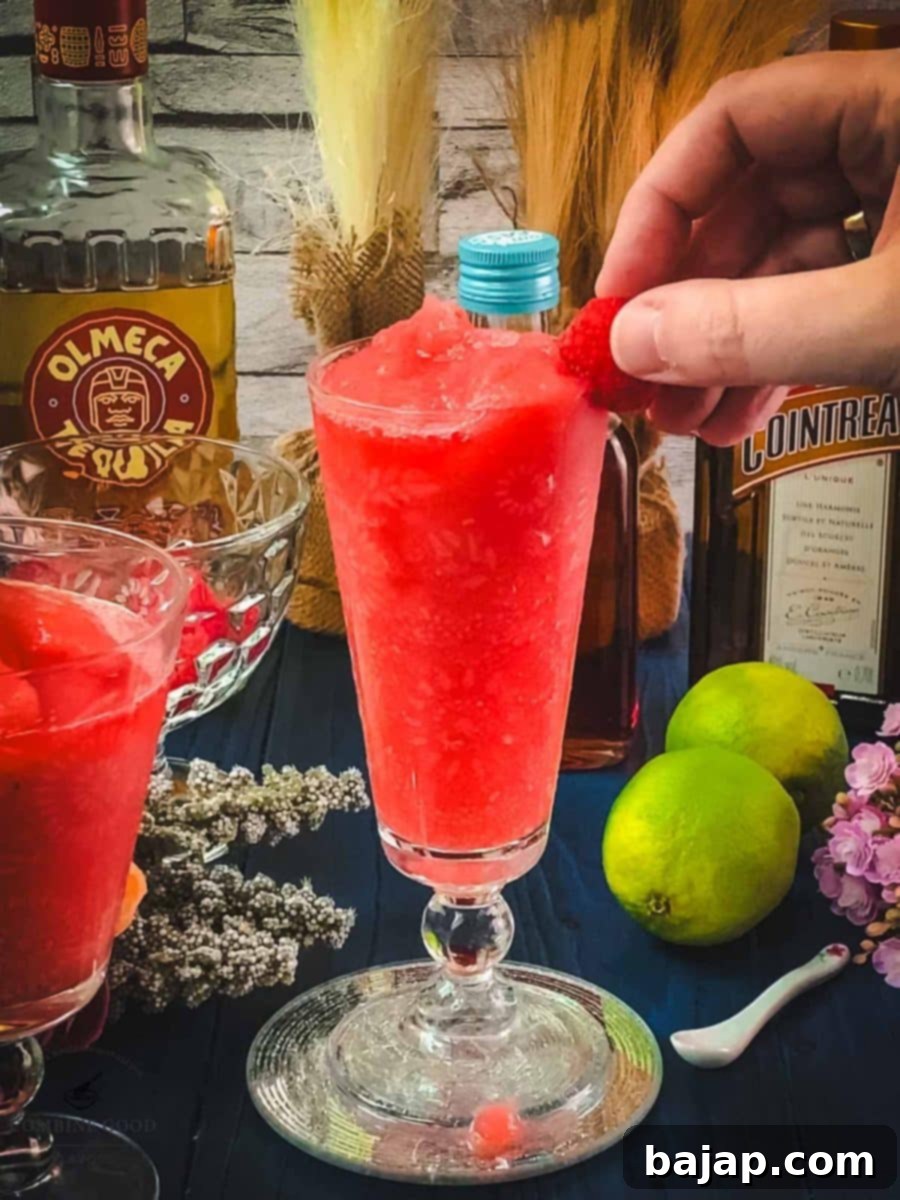 Raspberry Chill Margarita 11 Garnishing the vibrant pink frozen raspberry margarita with a fresh raspberry on the rim for a beautiful finish.