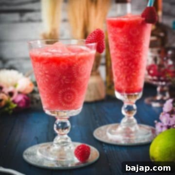 Raspberry Chill Margarita 16 A frosty glass of frozen raspberry margarita, garnished with fresh raspberries, ready to be enjoyed.
