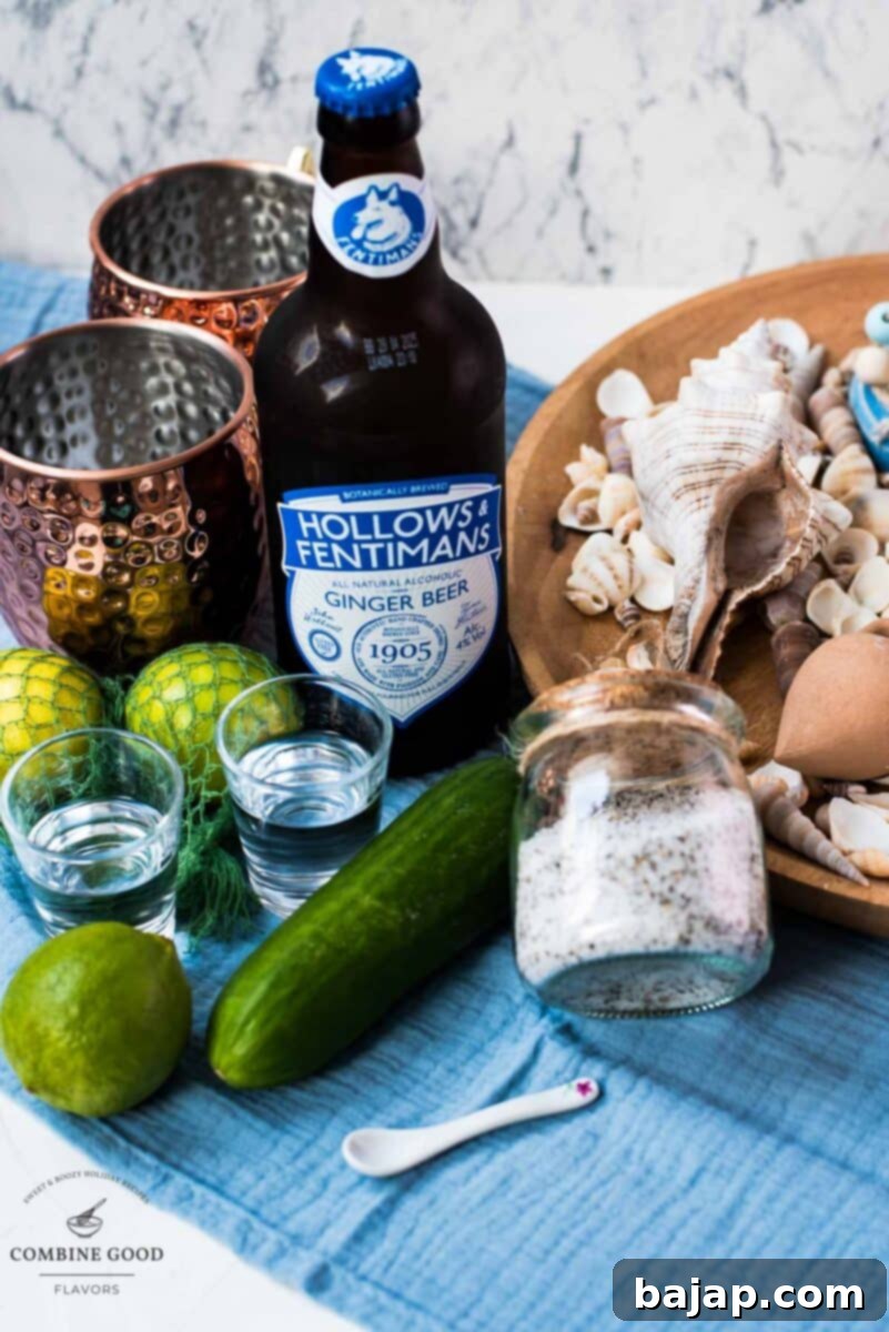 Essential ingredients for a mint cucumber Moscow mule: fresh limes, thinly sliced cucumber, homemade mint sugar, clear unflavored vodka, and bottled ginger beer, arranged on a rustic wooden surface.
