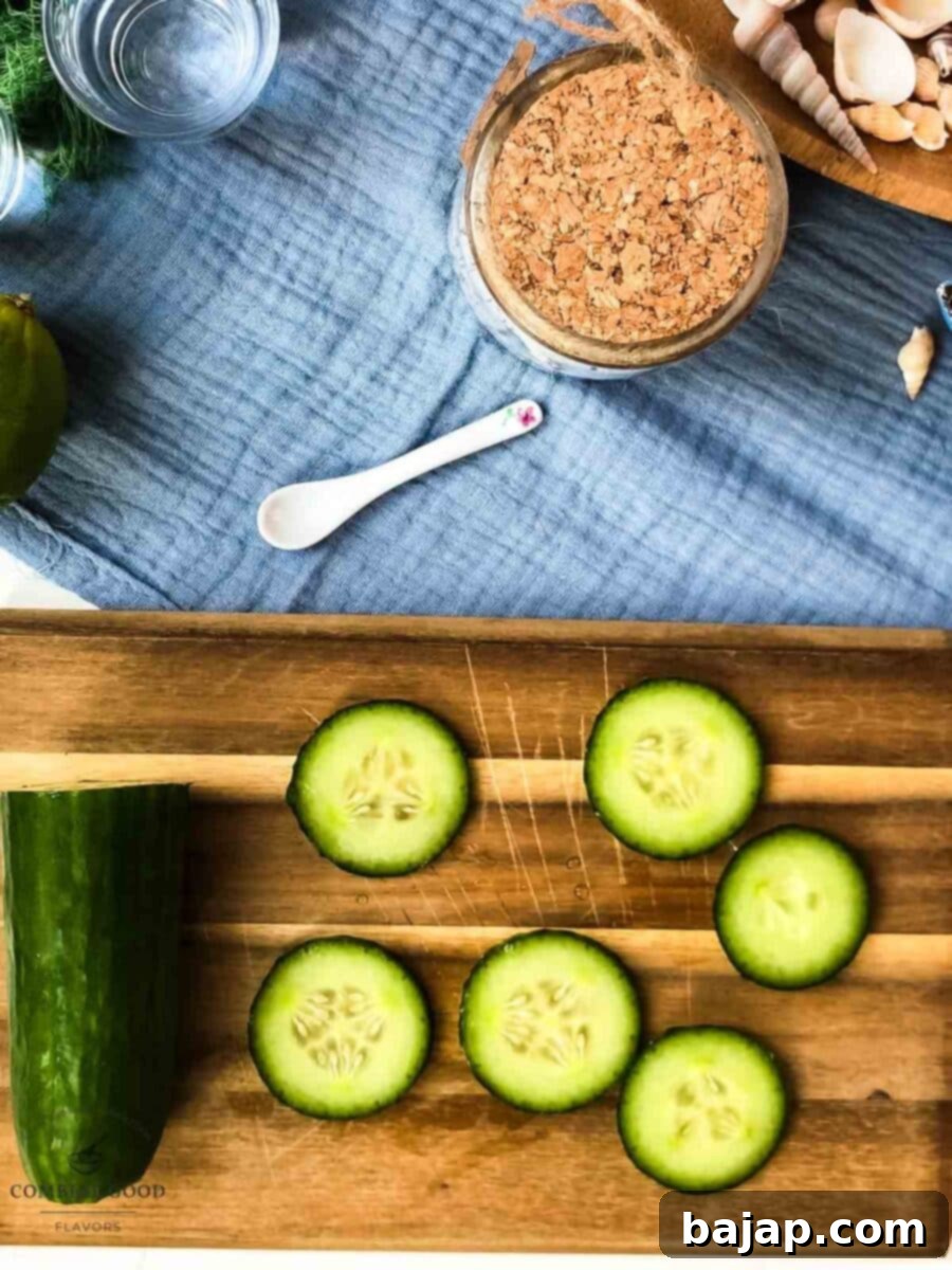 A hand thinly slicing a mini cucumber on a cutting board, preparing it for the Moscow Mule recipe.