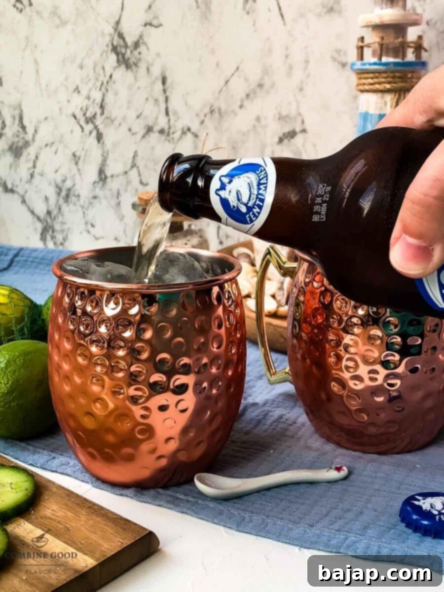 Topping a copper mug with ginger beer, the final main ingredient for a sparkling Moscow Mule.