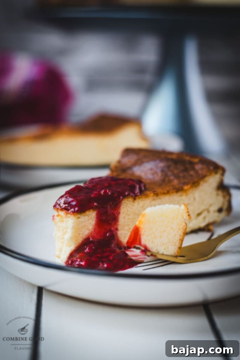 A slice of creamy baked semolina cheesecake with a vibrant homemade raspberry topping, served on a black and white patterned plate.