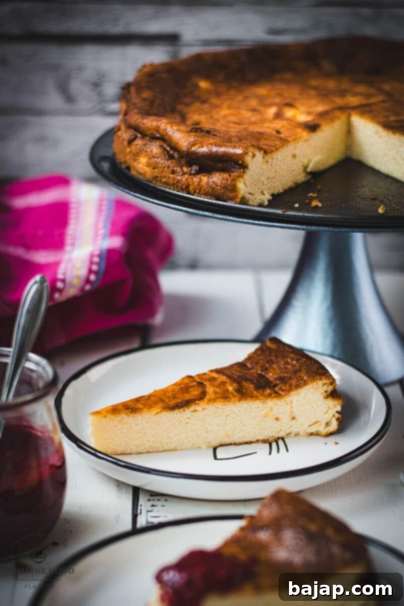 A beautifully sliced portion of creamy semolina cheesecake topped generously with vibrant raspberry sauce, ready to be enjoyed as a perfect dessert.